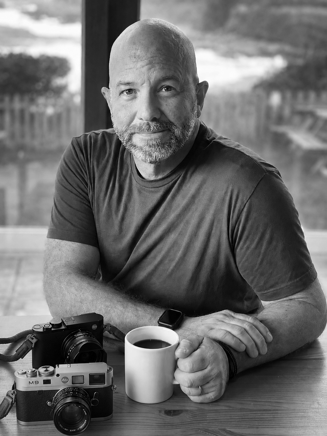 Horatio Franco seated at a table with two Leica cameras and a cup of coffee